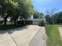 Brick ranch style home with a long driveway and a well-maintained front yard and mature trees at 9783 Lee Ct, Columbus, IN 47203