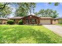 Lovely brick home featuring an attached two-car garage and a spacious front yard with mature trees at 3331 Loral Dr, Anderson, IN 46013