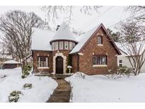 Brick home with snow covered lawn and unique turret at 35 E 56Th St, Indianapolis, IN 46220