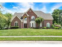 Traditional brick home with well-manicured lawn, mature trees, and a welcoming front entrance at 8819 Anchor Bay Ct, Indianapolis, IN 46236