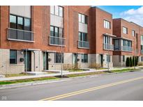 Modern townhomes boast red brick exteriors, balconies, and well-maintained landscaping along a city street at 806 7Th St, Columbus, IN 47201