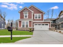 Two-story red brick home with white trim and a two-car garage at 15881 Tharp Woods Dr, Fishers, IN 46037