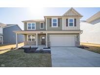 Two-story home showcasing a two car garage, covered porch, and a lush lawn at 9141 Blue Hill St, Indianapolis, IN 46239