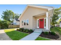 Tan house with red door, landscaped lawn, and walkway at 1320 Pearl St, Columbus, IN 47201