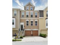 Brick three-story townhome with two-car garage and landscaped front yard at 621 Greenford W Trl, Carmel, IN 46032