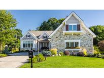 Charming stone-faced house with a well-manicured lawn and beautiful landscaping at 340 Beechwood Farm Ln, Indianapolis, IN 46260