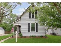 Charming home with gray siding, black shutters, and a cozy front porch adorned with an American flag at 47 Meadow Dr, New Palestine, IN 46163