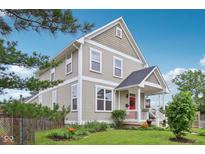 Attractive two-story home with manicured lawn, appealing landscaping, and inviting front porch with a bright red door at 2434 N Pennsylvania St, Indianapolis, IN 46205