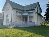 Quaint yellow house with green roof, porch, and small yard at 902 W Main St, Greenfield, IN 46140