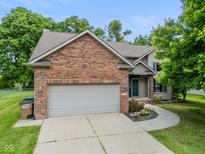 Charming home boasts a brick front, two-car garage, and beautifully landscaped yard with a curved sidewalk at 1936 Broadmoor Ln, Columbus, IN 47203