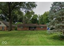 Charming ranch-style home featuring a brick facade and a well-maintained lawn, framed by mature trees at 9634 Maple Dr, Carmel, IN 46280