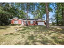 Charming red brick home with attached garage and a well-maintained yard surrounded by mature trees at 236 Bixler Rd, Indianapolis, IN 46227