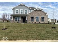 Two story home with gray siding and brick accents, featuring a covered porch and lush lawn at 7012 Pinnacle Dr, Columbus, IN 47201