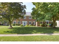 Charming two-story brick home with a well-manicured lawn and mature shade trees at 1487 Brook Mill Ct, Carmel, IN 46032