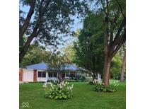 Charming brick home featuring a lush front yard with mature trees and landscaped flower beds at 1322 Greenway Dr, Anderson, IN 46011