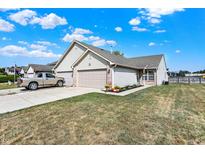 Charming ranch-style home featuring a two-car garage, well-manicured lawn, and inviting curb appeal set under a sunny sky at 828 Ashton Park Dr, Greenwood, IN 46143