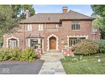 Stunning brick home featuring a beautiful stone walkway, mature landscaping, and an arched wood front door at 5650 N Meridian St, Indianapolis, IN 46208