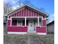Charming single-story home featuring a cozy front porch with a white door and magenta siding at 1049 N Tremont St, Indianapolis, IN 46222