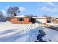 Brick ranch house with attached garage, snowy front yard, and driveway at 4036 Ridgeway Dr, Indianapolis, IN 46221