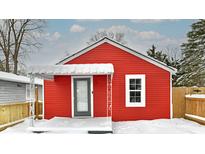 Red cottage with white trim, snow covered porch and yard, and wooden fence at 1504 Martin St, Indianapolis, IN 46227