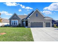 Charming brick home featuring a 3-car garage, well-manicured lawn, and a welcoming front porch at 19400 Scofield Ridge Blvd, Westfield, IN 46062