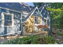 Charming blue home showcasing a stone accent, flower boxes on the porch and a landscaped garden at 327 Central Ave, Anderson, IN 46012