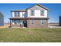 Two-story home showcasing a brick and vinyl exterior, complemented by a well-maintained lawn under a clear blue sky at 7888 Magnolia St, New Palestine, IN 46163