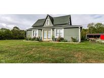 Charming home with fresh green siding, colorful roses along the front, and a well-manicured lawn at 6572 S 300 W, Trafalgar, IN 46181