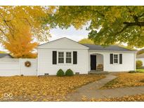 Charming single-story home with white siding, black shutters, and a well-maintained front yard filled with fall leaves at 610 E Morgan St, Martinsville, IN 46151