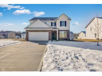 Two-story home with brick and white siding, a two-car garage, and a snow-covered front yard at 4779 E Shadowbrook Dr, Camby, IN 46113