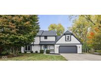 Charming two-story home with a gray roof, white painted brick, a dark gray garage door, and a well-maintained front yard at 10768 Courageous Dr, Indianapolis, IN 46236