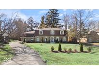 Charming stone-clad home featuring a well-manicured lawn and an asphalt driveway at 6906 Johnson Rd, Indianapolis, IN 46220