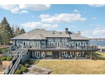 Expansive gray brick home with large deck overlooking the lake and well-maintained landscaping at 9447 Promontory Cir, Indianapolis, IN 46236