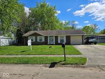 Charming single-story home featuring a well-maintained lawn, attached garage, and convenient carport at 6031 Wixshire Dr, Indianapolis, IN 46254