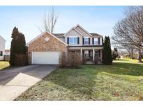 Inviting two-story home boasts a brick facade, covered porch, and well-manicured lawn at 719 Trent Dr, Greenwood, IN 46143