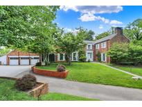 Charming brick home with lush landscaping, mature trees, and a spacious driveway leading to the garage at 2505 Riverside Dr, Columbus, IN 47201