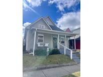 Charming grey home with a welcoming front porch, featuring white railings and a lovely wreath on the front door at 1709 Hoyt Ave, Indianapolis, IN 46203