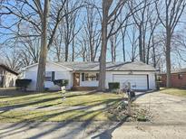 Charming single-story brick house featuring an attached garage and a well-maintained front yard and mature trees at 8637 Skyway Dr, Indianapolis, IN 46219
