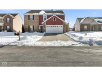 Two-story brick and red-sided home with a white garage door and snow-covered yard at 2687 Wildflower Ln, Greenwood, IN 46143