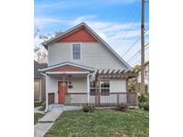 Charming two-story home features a welcoming front porch with a pergola and an orange front door at 444 N Keystone Ave, Indianapolis, IN 46201