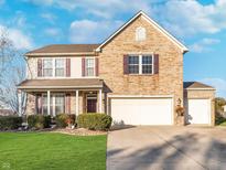 Charming two-story home with a brick facade, manicured lawn, and a two-car garage on a sunny day at 8618 Talisker Dr, Avon, IN 46123