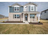 Charming two-story home boasts a modern exterior with a combination of brick and blue siding and manicured lawn at 7904 Magnolia St, New Palestine, IN 46163