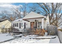 Cute bungalow with covered porch, snow-covered yard, and charming landscaping at 5441 E 17Th St, Indianapolis, IN 46218