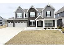 Charming two-story home with a three car garage, covered porch, and manicured front yard at 10811 Wild Orchard Ln, Indianapolis, IN 46239