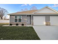 Gray siding two-car garage home with a landscaped lawn and white fence at 1501 Coen Ct, Columbus, IN 47201