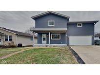 Charming two-story home featuring a covered porch, attached garage, and well-maintained lawn at 2933 Merts Dr, Indianapolis, IN 46237