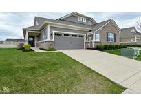 Beautiful home showcasing a concrete driveway, gray siding, brick accents, lush lawn and attached two car garage at 17345 Northam Dr, Westfield, IN 46074