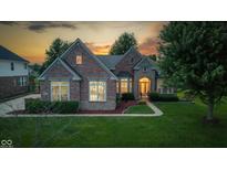 Beautifully lit brick home at sunset, showcasing its architectural details and lush green lawn at 10346 Strongbow Rd, Fishers, IN 46040