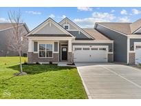 Charming home showcasing stone accents, a manicured lawn, and a spacious two-car garage at 16946 Cattle Hollow Ln, Noblesville, IN 46060