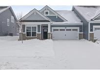 Charming home exterior features stone accents, two-car garage, covered porch, and snow-covered driveway at 16946 Cattle Hollow Ln, Noblesville, IN 46060